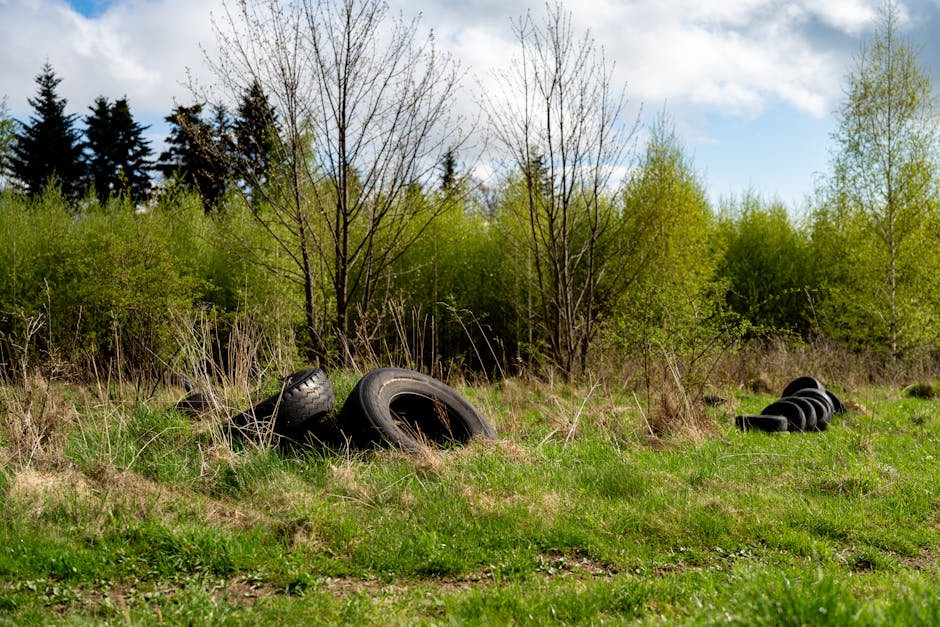 Close-up of a black cylindrical pole with a warning sign in white text stating a fine of $1000 for littering. The sign is centered on the pole, which appears to be made of metal or painted plastic, wi
